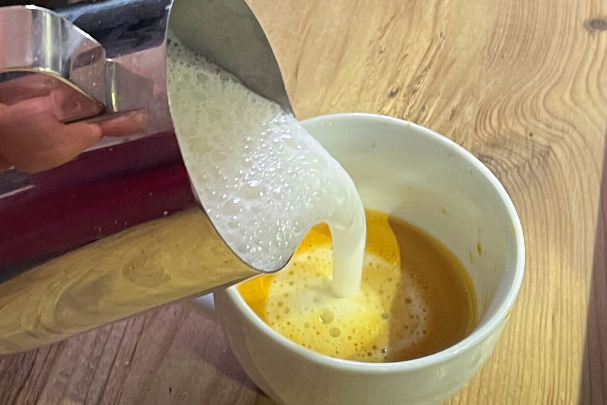 Cappuccino-Zubereitung Milch wird in den Cappuccino gegossen